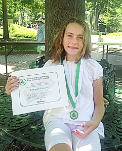Ella Spremulli proudly displays her CLSC Young Readers medallion and certificate. She received the awards from the CLSC Veranda for reading 16 books from the program’s historic list.